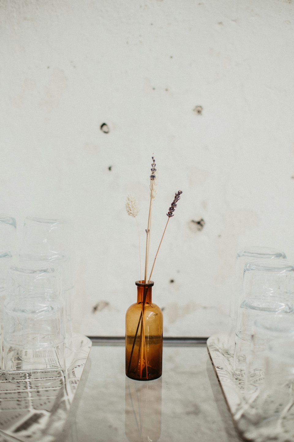 Bernsteinfarbene Flasche mit getrocknetem Lavendel auf einer reflektierenden Oberfläche.